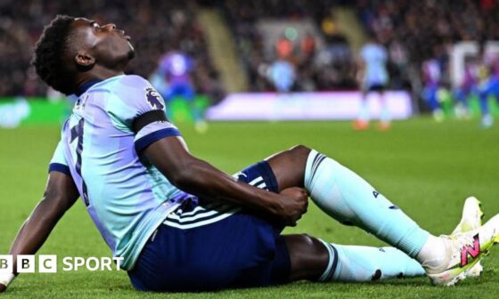 Arsenal's Bukayo Saka holds the back of his leg as he sits on the field after suffering an injury against Crystal Palace