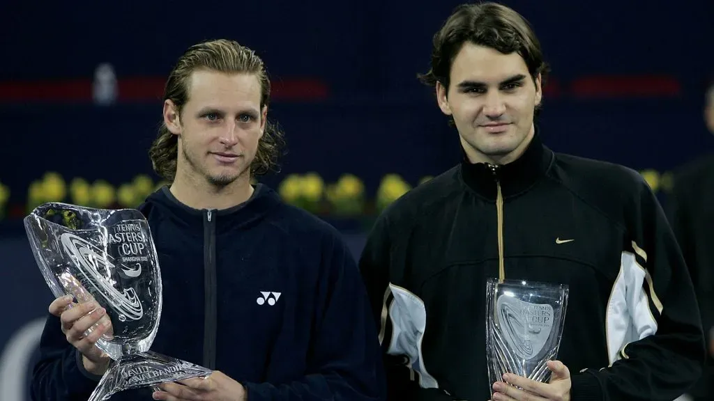 David Nalbandian holds the trophy as Roger Federer looks on after his five set victory against Roger Federer in the 2005 Masters Cup. (Clive Brunskill/Getty Images)