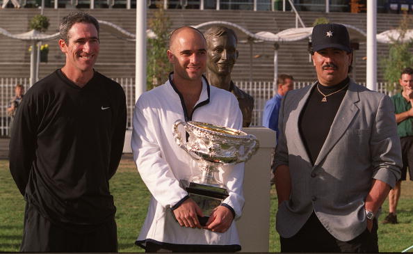 Andre Agassi of the USA stands with his Australian Open Trophy next to a bust of Rod Laver with Coach Brad Gilbert and Gil Reyes after his win agai...