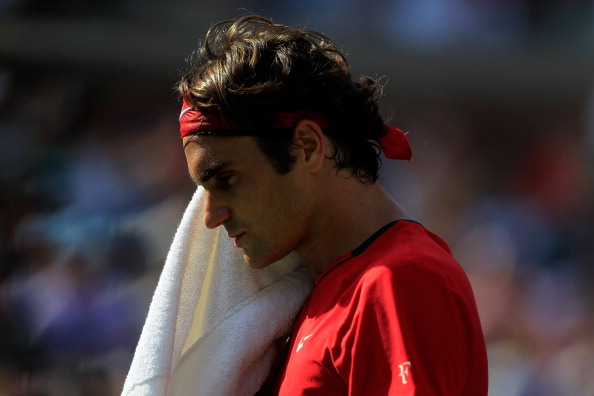 Roger Federer of Switzerland wipes his face with a towel against Novak Djokovic of Serbia during Day Thirteen of the 2011 US Open at the USTA Billi...