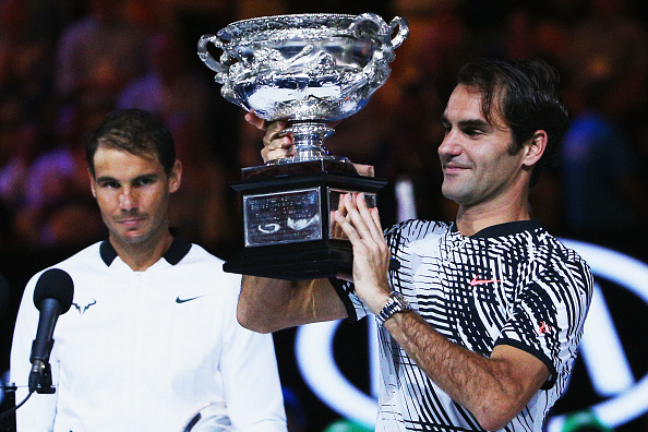 A defeated Raphael Nadal of Spain reacts as Roger Federer of Switzerland celebrates with the Trophy after winning in the Men's Final match against ...